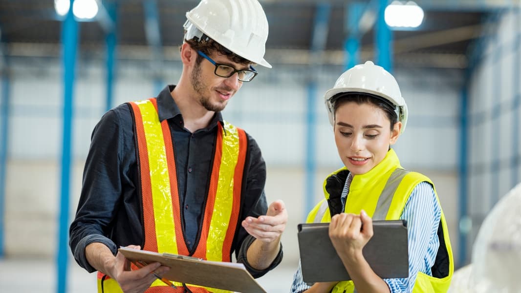 Two Quality Engineer discussing by tablet talking in warehouse floor of factory. Production and Quality control system. - stock photo