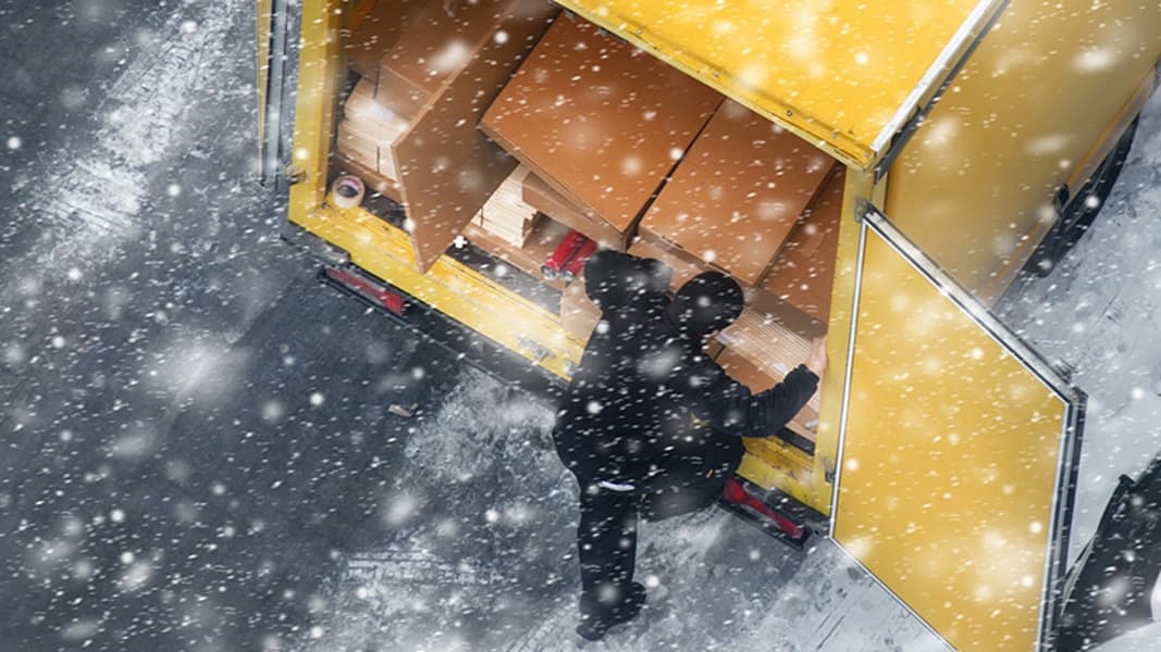 Elevated view of yellow delivery truck on frozen city street during snowing.
